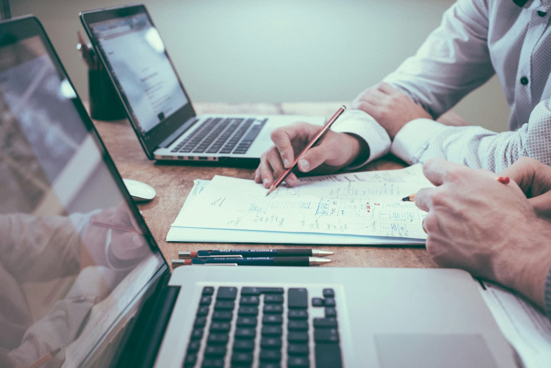 Consultores trabajando con portátiles y documentación estratégica sobre la mesa